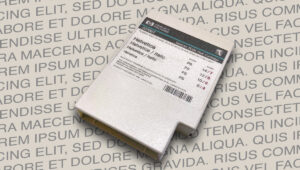 Das Bild zeigt eine alte Font Cartridge mit der Schriftart Helvetica auf einem Untergrund aus Buchstaben