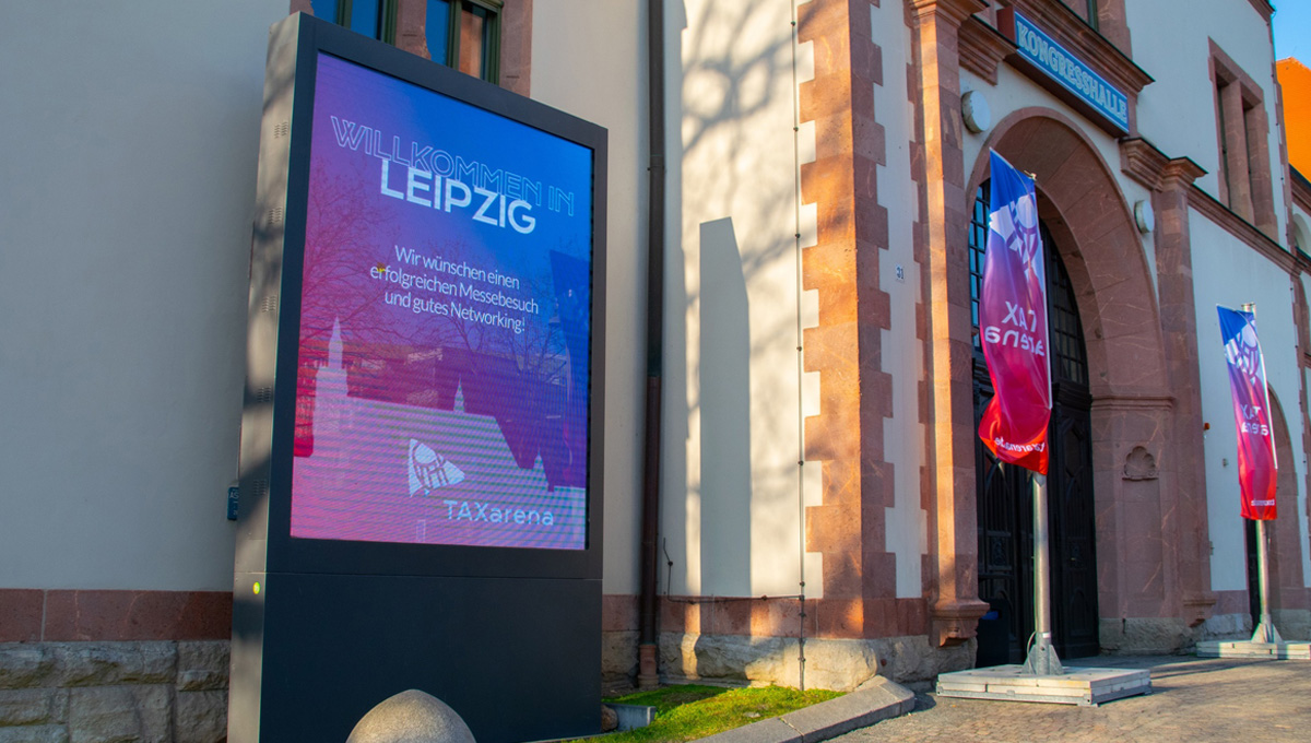 sobotta-it-auf-der-taxaena-leipzig Eingang der Kongresshalle am Zoo Leipzig mit Fahnen und Beschilderung der TAXarena 2026